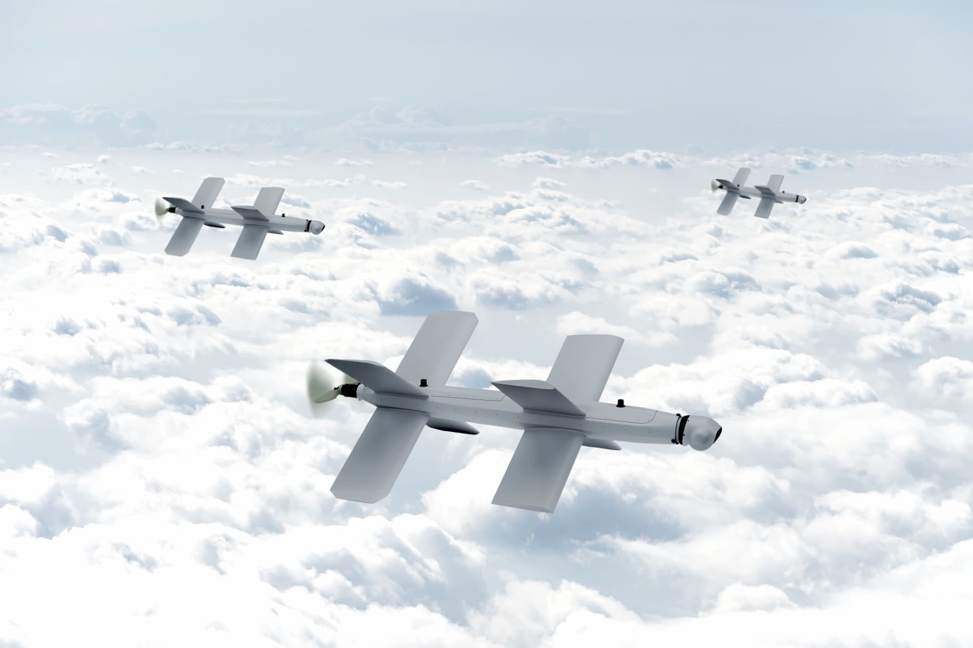 Three drones with fixed wings and propellers fly above the clouds in a clear sky.